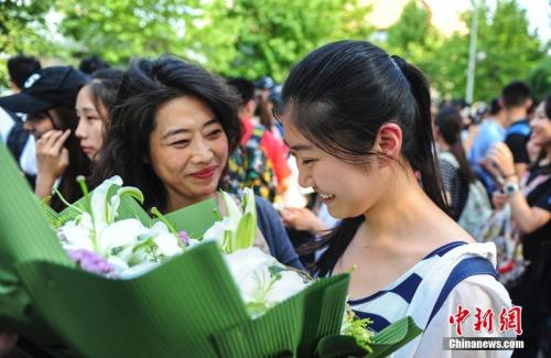 資料圖：山東濟(jì)南眾多考生手捧鮮花在家長(zhǎng)的簇?fù)硐職g快告別高考。中新社記者 張勇 攝