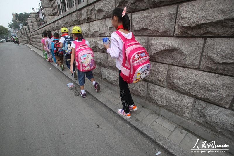 2013年09月11日，濟(jì)南運(yùn)署街上，小學(xué)生走史上“最窄人行道”上學(xué)。