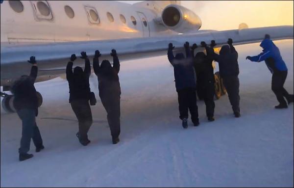伊加爾市一架客機起飛前被凍在了跑道上。飛機上的乘客不得不下來推飛機。