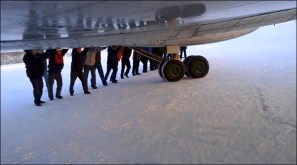 　伊加爾市一架客機起飛前被凍在了跑道上。飛機上的乘客不得不下來推飛機。