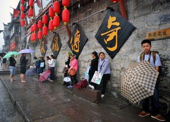 　4月29日上午11時20分，一些游客和古城當(dāng)?shù)氐木用穸阍谝粋€酒吧的屋檐下避雨。這些當(dāng)?shù)鼐用褚詾橛慰团恼罩\生，一場降雨讓他們的生意更加清淡。