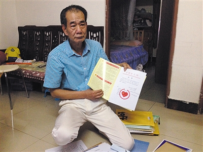 翻出一家網(wǎng)站贈予的“中國好人”證書，區(qū)少坤單膝跪在地上，“你看，我是中國好人啊?！?范春旭 攝