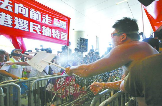 17日，在香港立法會外，一名反對政改的男子向支持派人群投擲標(biāo)牌。