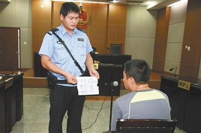 昨日庭審中，法警向趙某出示其扎完車胎后所留辱罵公司的紙條。通訊員 李秀文 攝