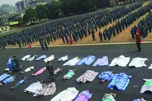20多名女生躺在瀝青跑道上，身上嚴嚴實實地裹著棉被，接受太陽的照曬。