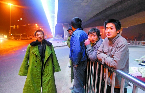 冬夜里，農(nóng)民工在橋下等著干活兒。