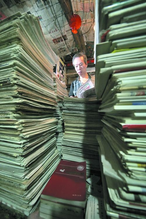 王曉民坐在寫字桌前，被報紙淹沒。