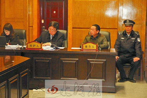 庭審現(xiàn)場，被告人坐在律師身旁為自己辯護(hù)。
