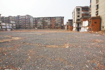 為降塵，旮旯王村拆遷后裸露的地面上鋪了一層石子。