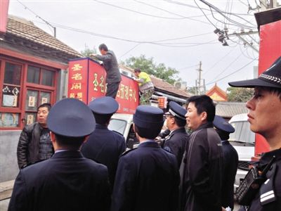 昨日下午,東城區(qū)工商、城管、公安等部門,對雍和宮附近的預(yù)測中心進(jìn)行清理整頓,站在車頂?shù)膬擅と苏鸪患摇邦A(yù)測中心”的招牌。因雍和宮、白云觀等文化景點(diǎn)外聚集大量算命先生,被媒體稱為“算命一條街”。本版攝影/新京報(bào)記者 李寧 攝