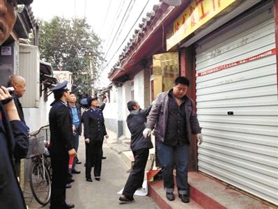 執(zhí)法人員拆除胡同里一家店面未經(jīng)審批的招牌。