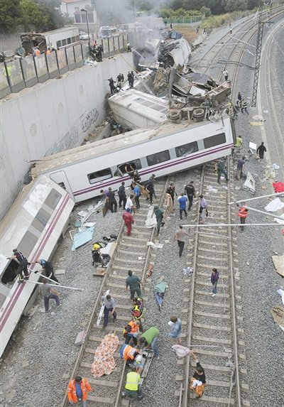 24日，救援人員在西班牙列車脫軌現(xiàn)場。一節(jié)車廂被強(qiáng)大的慣性拋上鐵道邊的高臺。