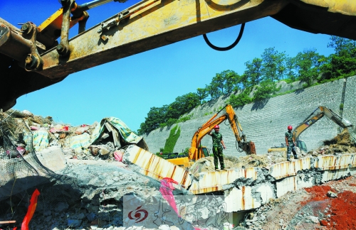 為確保道路盡早通車，工人師傅冒著烈日，指揮施工機械清理爆破現場