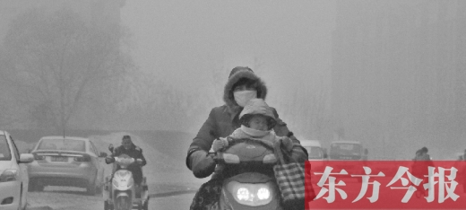 12月8日，鄭州市未來(lái)路上，一位市民帶著孩子在霧中騎行