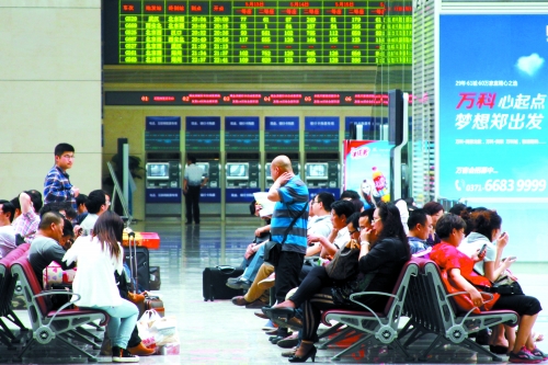 候車大廳溫度很高，一名乘客一手扇風(fēng)、一手擦汗