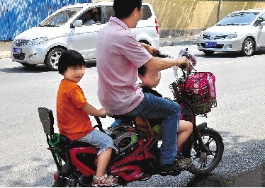 周先生騎著一輛低矮的電動(dòng)車帶著一對兒女，很不安全。