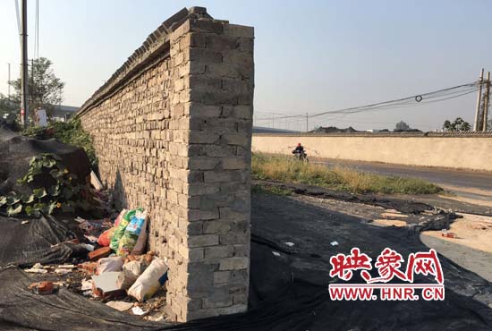 一墻之隔，一邊是道路，一邊是垃圾和荒草，市民質(zhì)疑其為遮羞墻。