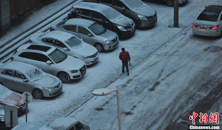 11月18日，行人在沈陽(yáng)街頭的積雪中穿行。
