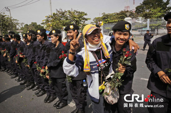 2013年12月03日,曼谷總理府與曼谷警署允許反政府示威民眾進(jìn)入,雙方進(jìn)入暫時(shí)“停戰(zhàn)”狀態(tài)迎接泰王生日。曼谷警察總署,女警們手持鮮花送給反政府示威民眾。圖片來源:Manish Swarup/東方IC