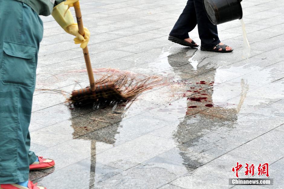 圖為環(huán)衛(wèi)工人在清理案發(fā)地點的血跡。