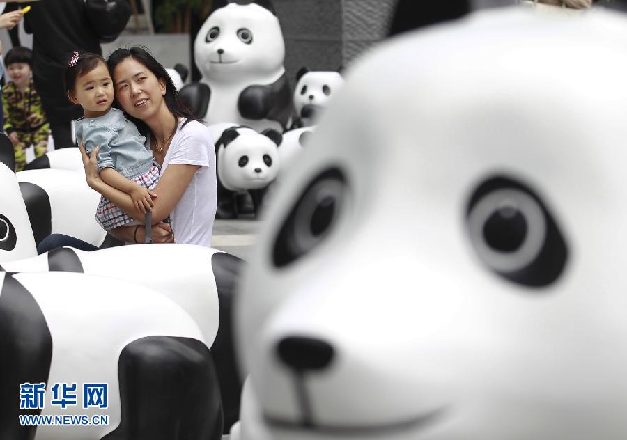 6月2日，一位家長帶著孩子在上海街頭和大熊貓模型合影。
