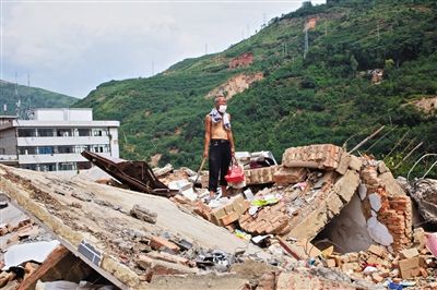 8月9日,龍頭山鎮(zhèn),一位老者在自家房屋廢墟上尋找家當(dāng)。