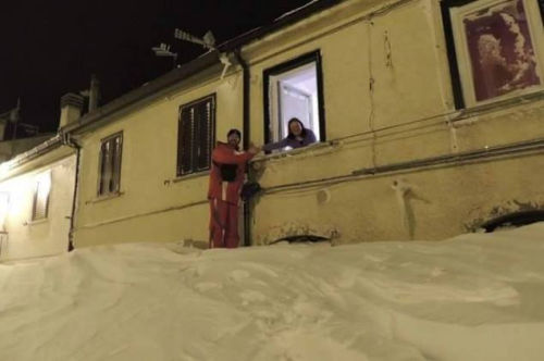 一個居民站在積雪上，可以與一名二樓鄰居在窗口握手。（來源：意大利氣象局）