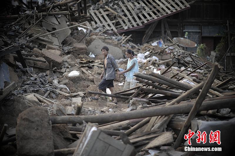 2014年8月5日，云南昭通龍頭山鎮(zhèn)老街，一對夫妻從居住房屋的廢墟中走過。
