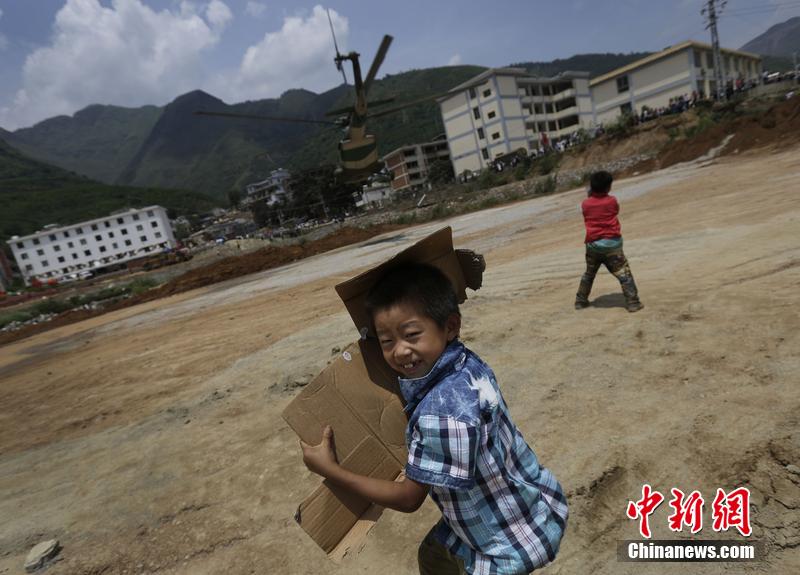 云南省昭通市魯?shù)榭h發(fā)生6.5級地震。幾個孩子在直升機降落的平地上玩耍。