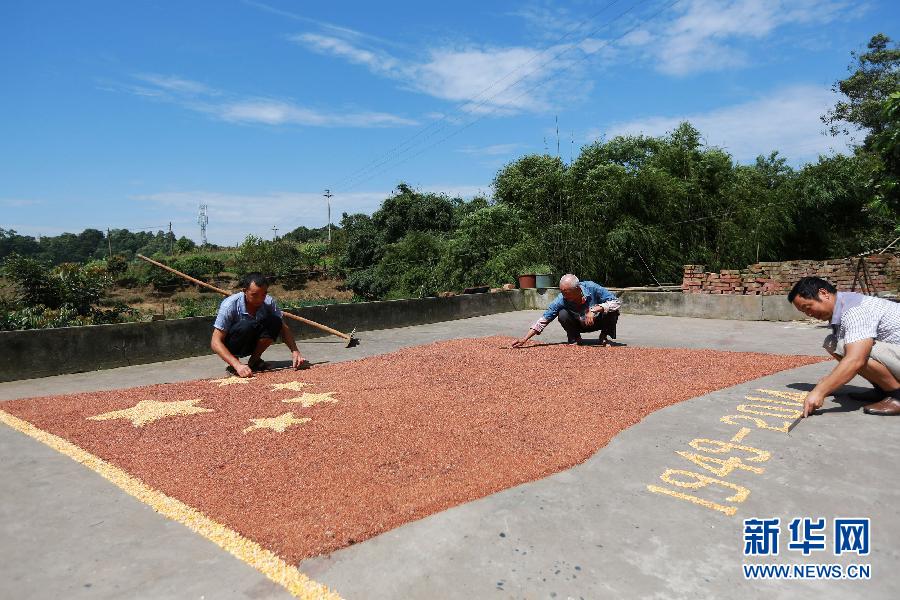 村民馬玉明（左一）用豐收的高粱和玉米在院壩里擺國(guó)旗為祖國(guó)慶生。