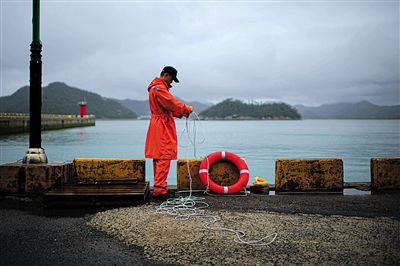 7月6日，韓國珍島，一名海岸警察在港口系救生圈。4月，客輪在珍島近海發(fā)生沉船事故后，仍有11人下落不明。