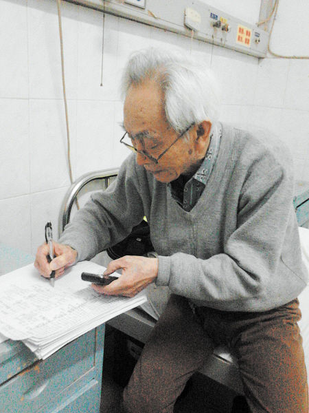 杜修源老人埋頭寫著特殊的“日記”。 李卓 攝