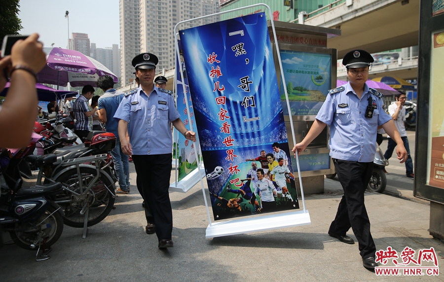 7月2日上午，鄭州市紫荊山地鐵站出入口，執(zhí)法人員抬著寫有勸導(dǎo)語的宣傳板，前往占道經(jīng)營攤位“圍觀執(zhí)法”